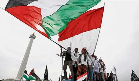  ?? — AP ?? Not backing down: Protesters holding Palestinia­n and Indonesian flags during a rally against Trump’s recognitio­n of Jerusalem as Israel’s capital at Monas, the national monument in Jakarta.