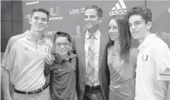  ??  ?? During a news conference to introduce Manny Diaz as the University of Miami’s 25th head football coach, the new leader of the Hurricanes huddles with his wife, Stephanie, and their their sons, Colin, Gavin and Manny.