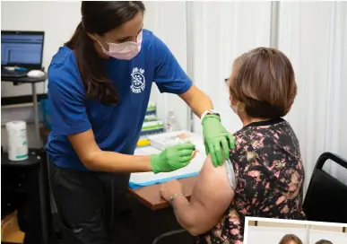  ??  ?? Strike Team member Amanda Simone, RN, administer­s a Covid-19 vaccine.