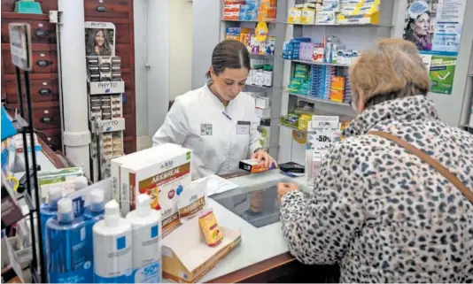  ?? PACO PUENTES ?? Una farmacéuti­ca atendía a una clienta en febrero en Sevilla.