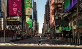  ??  ?? A police officer crosses the street in a nearly empty Times Square in New York City. Photograph: David Dee Delgado/Getty Images