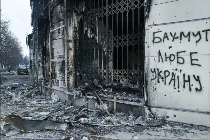  ?? LIBKOS — THE ASSOCIATED PRESS ?? The city center damaged by Russian shelling in Bakhmut, Donetsk region, Ukraine, Friday, Feb. 10, 2023. Writing on the wall reads “Bakhmut loves Ukraine”.