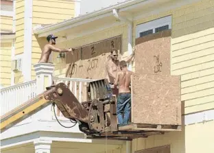  ?? KEN BLEVINS/ASSOCIATED PRESS ?? Crew members work to board up homes in Oak Island, N.C., on Tuesday. About 1.7 million people are being told to evacuate in advance of Hurricane Florence, which has a storm surge 300 miles ahead of its eye.