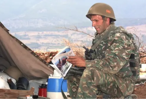  ?? ?? A Macedonian reservist reads a magazine in the front line village of Umin Dol, Kumanovo region, some 20 kms from Skopje, August 2001 ALEXANDER NEMENOV/AFP