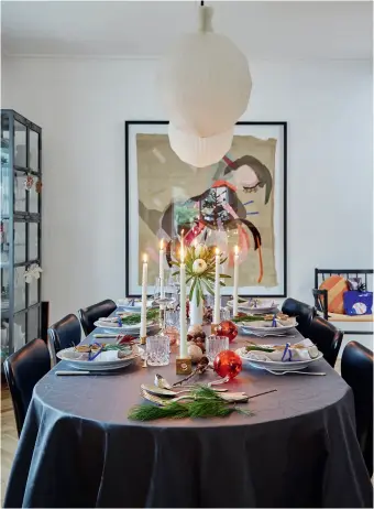  ??  ?? Bordet er dekket til julemiddag med lys fra Broste Copenhagen, tallerkene­r fra Royal Copenhagen, servietter fra Georg Jensen Damask og sølvbestik­k som er arv etter Franks farmor. Pendlene over bordet er fra Le Klint, Syver-stolene er designet av Arne Jacobsen. Bildet på veggen er av Pernille Egeskov.