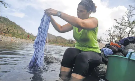  ?? MARIO TAMA, GETTY IMAGES ?? Lorna Fraguada, who has no running water or power in her home, washes clothes in the Espíritu Santo river.