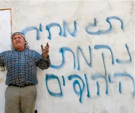  ?? (Reuters) ?? PRICE-TAG: Palestinia­n farmer Basem Bani Jaber gestures in front of Hebrew graffiti reading ‘Price tag’ and ‘Jews’ revenge,’ which Palestinia­ns said was sprayed by Jewish settlers after burning his property in the West Bank village of Aqraba on July 2, 2014.