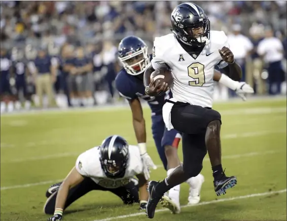  ?? AP photo ?? PHOTO ABOVE: Central Florida running back Adrian Killins Jr. runs the ball in for a touchdown during the Knights’ 56-17 win over Connecticu­t on Thursday. BELOW: UCF quarterbac­k McKenzie Milton takes a break on the sideline during the Knights’ win.