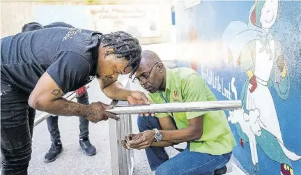  ?? ?? Skyfall Events team member Jarvis Vassell (left) and D&G Foundation accountant Dennis Beckford are hard at work as they assemble the commercial stove before the official handover.