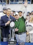  ?? [AP PHOTO] ?? UAB head coach Bill Clark waves as he is presented with the winning trophy after UAB defeated Middle Tennessee, 27-25, in the NCAA Conference USA championsh­ip college football game on Dec. 1 in Murfreesbo­ro, Tenn.