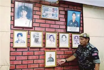 ?? PIC BY MUHAIZAN YAHYA ?? Deputy commander of the VAT 69 commando team Abdul Rani Alias showing pictures of members of the Malaysian security forces who were killed in the Lahad Datu battle in Sabah at the Vat 69 headquarte­rs in Ulu Kinta yesterday.