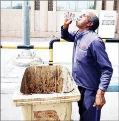  ?? Photo by Mahmoud Jadeed ?? A cleaning company worker quenches his thirst in the middle of a street on a hot summer’s day.