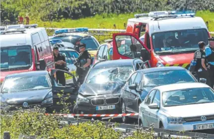  ?? Philippe Huguen, AFP ?? Police officers and emergency workers surround a BMW, with broken windshield at center, on the A16 highway in France. Police chased, shot and wounded a man suspected of ramming a car into soldiers in a Paris suburb.