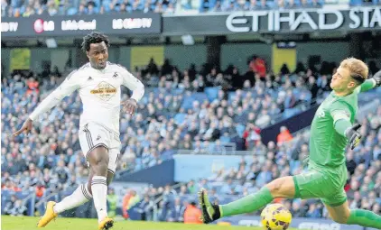  ??  ?? > Wilfried Bony slots home beyond Joe Hart in the Manchester City goal during 2014