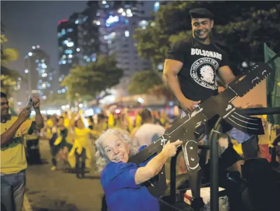  ??  ?? ► Una seguidora de Bolsonaro posa mientras juega con una ametrallad­ora de cartón, durante la celebració­n electoral en Río.