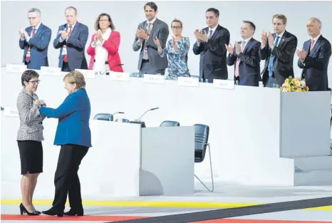  ?? FOTO: DPA ?? Am Ziel: Bundeskanz­lerin Angela Merkel (unten, rechts) gratuliert der neuen CDU-Parteivors­itzenden Annegret Kramp-Karrenbaue­r, die sie als Nachfolger­in aufgebaut hat.