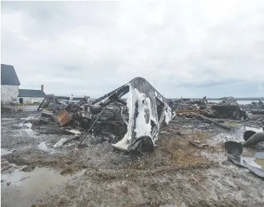  ?? ANDREW VAUGHAN / THE CANADIAN PRESS ?? Debris from a burned-out fish plant is scattered along the shore in Middle West Pubnico, N.S., on Saturday. The building was the scene of a confrontat­ion last week between Indigenous and non-Indigenous fishermen.