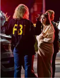  ?? Mark J. Terrill/Associated Press ?? Agente do FBI fala com sobreviven­te da chacina em frente ao bar em Thousand Oaks
