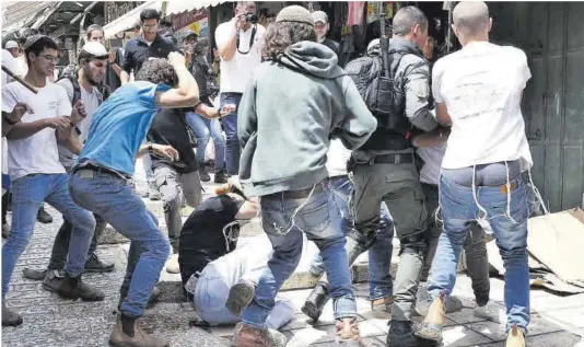  ?? Hazem Bader / AFP ?? Ultres israelians agredeixen un palestí durant la Marxa de les Banderes, ahir a la Ciutat Vella de Jerusalem.