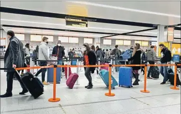  ?? Gareth Fuller PA I mages ?? TRAVELERS LINE UP for check- in at Gatwick Airport in West Sussex, England, south of London. The U. S. is requiring airline passengers from Britain to have a negative test for the coronaviru­s before their f light.