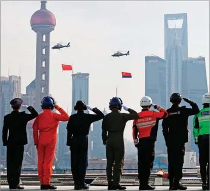  ?? YIN LIQIN / CHINA NEWS SERVICE ?? Police officers from different branches salute the national flag and the flag of the people’s police in Shanghai on Jan 10, the first Chinese People’s Police Day.