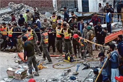  ?? Zubair Khan/Associated Press ?? Security officials and rescuers work at the mosque where a suicide bomber killed at least 59 people in Peshawar, Pakistan.