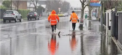  ?? Photo: RNZ / Niva Chittock ?? New Zealand workers try and clear gutters in Edgeware in Christchur­ch during heavy rain last month.