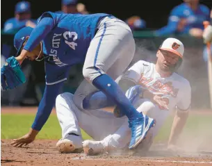  ?? JULIO CORTEZ/AP ?? Trey Mancini, right, scores ahead of a tag attempt by Royals starting pitcher Carlos Hernandez during the fifth inning Monday in Baltimore. Mancini scored on a wild pitch in the Orioles’ 6-1 victory.