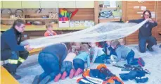  ?? FOTO: FEUERWEHR ?? In einem Zimmer voller Rauch bewegt man sich am sichersten nah am Boden. Das haben die Mädchen und Jungen beim Feuerwehrt­ag im Kindergart­en Eigenzell geübt. Das weiße Tuch war der Rauch.