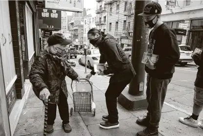  ?? Jim Wilson / New York Times ?? Max Leung, center, and actor Will Lex Ham offer a booklet that explains how to report a hate crime to a woman in San Francisco’s Chinatown following a fatal attack on an older Thai man who was defenseles­s.