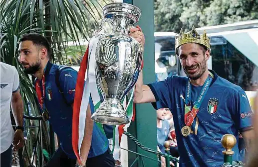  ?? Foto: AFP ?? Giorgio Chiellini präsentier­t den Fans stolz die Trophäe, auch Torhüter Gianluigi Donnarumma (l.) freut sich.