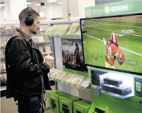  ?? TIMOTHY CLARY/AFP/Getty
Imag es ?? A customer looks at a display of Microsoft’s next-generation console, the Xbox One, at a store in New York City.