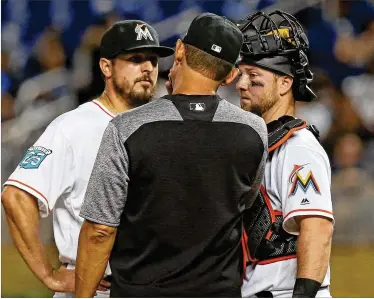  ?? DAVID SANTIAGO / MIAMI HERALD ?? Miami Marlins pitcher Caleb Smith talks with Marlins pitching coach Juan Nieves and catcher Bryan Holaday during the third inning Thursday at Marlins Park. Smith gave up four runs in the inning in Miami’s 7-0 loss.