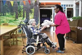  ?? PHOTOS BY ILVY NJIOKIKTJI­EN/NEW YORK TIMES ?? Anna Leeman-Koning is handed a therapeuti­c animatroni­c seal at a care facility in Amsterdam. Dutch dementia care uses tools like the seal, which brings out old emotions, momentaril­y sweeping away disorienta­tion.