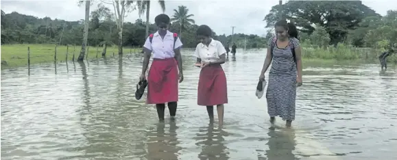  ?? Photo: Fonua Talei ?? Adi Cakobau School Year 11 students, (from left), Luisa Soqo, 16, Miriama Laivou, 16, and Mere Fetatuki, 16, wade through flood waters in Naitasiri on January 15, 2018.