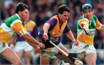  ??  ?? Offaly’s Martin Hanamy (left), always one for a word in Tom’s ear after half-time, joining forces with Colm Cassidy in a bid to stop the run of Wexford’s Adrian Fenlon in the Leinster championsh­ip of 1997.
