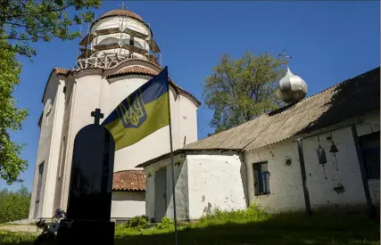  ?? Francisco Seco/Associated Press ?? A Ukrainian flag waves next to the old, right, and new Church of the Intercessi­on of the Blessed Virgin Mary, in Lypivka, Ukraine. Two years ago it also provided refuge from war.