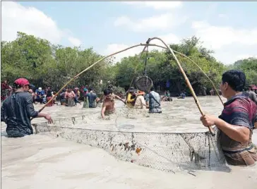  ?? YOUSOS APDOULRASH­IM ?? Men use a traditiona­l Khmer fishing net contraptio­n at the fishing festival.