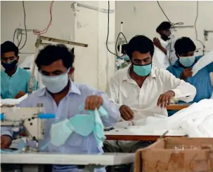  ?? — AP ?? SUPPLY LINE: Workers make face masks in Karachi amid the outbreak of the coronaviru­s.