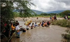  ?? Photograph: Schneyder Mendoza/AFP/Getty ?? Migrants cross the Táchira River, on the Venezuelan-Colombian border, last year, when the official crossing was closed due to Covid.