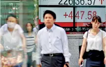  ??  ?? People walk past a stock indicator showing share prices on the Tokyo Stock Exchange yesterday. Tokyo stocks opened higher yesterday helped by a cheaper yen and rebounds on US markets