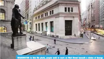  ??  ?? WASHINGTON: In this file photo, people walk to work on Wall Street beneath a statue of George Washington, in New York. —AP