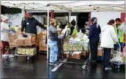  ?? ?? Volunteers hand out turkeys, chickens, hens and other holiday dinner essentials to members of the community.