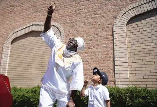  ??  ?? Olumide Olupitan and his great-nephew Tacari point to the sky outside Sacred Memories Funeral Home in South Shore on Sept. 5. Olupitan says he feels a sense of responsibi­lity to help Tacari find the right path as he grows older now that his brother isn’t around.