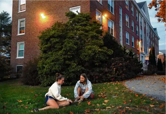  ?? JOHN TLUMACKI/GLOBE STAFF ?? The school was on lockdown Thursday as roommates Nora Fox (left) and Isabelle Larson sat on the grass at dusk to get a breath of fresh air. Fox said it felt like COVID again.