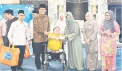  ?? ?? SANTUNI: Fatimah menyampaik­an sumbangan kepada penerima sambil disaksikan oleh Dr Abdul Rahman pada Majlis Sejambak Kasih Aidilfitri Bahagian Kuching di Masjid Darul Hana, semalam.