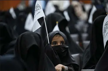  ?? AAMIR QURESHI ?? A veiled girl holds a Taliban flag during a gathering of female students before a pro-taliban rally Saturday at the Shaheed Rabbani Education University in Kabul, Afghanista­n.