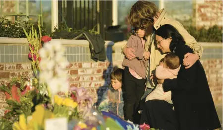  ?? ASHLEY LANDIS/AP ?? A family gathers at a memorial near the Star Ballroom Dance Studio in Monterey Park, Calif. A gunman killed multiple people at the studio.