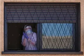  ?? Photograph: Baldesca Samper/AFP via Getty Images ?? A member of the Military Emergencie­s Unit appears at a window during a disinfecti­on in the Getafe suburb of Madrid on 25 March.