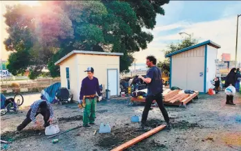  ?? Liz Jacobs ?? Volunteers construct tiny houses for homeless people who had been camping on a median in Oakland. The developmen­t of 11 small homes was organized by the Village, an advocacy group.